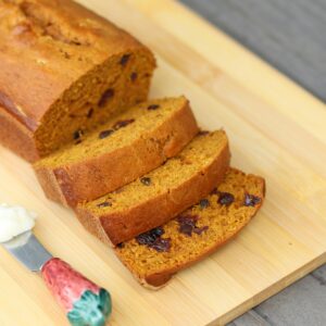 Freshly baked pumpkin bread with raisins on a cutting board, perfect for a cozy meal.